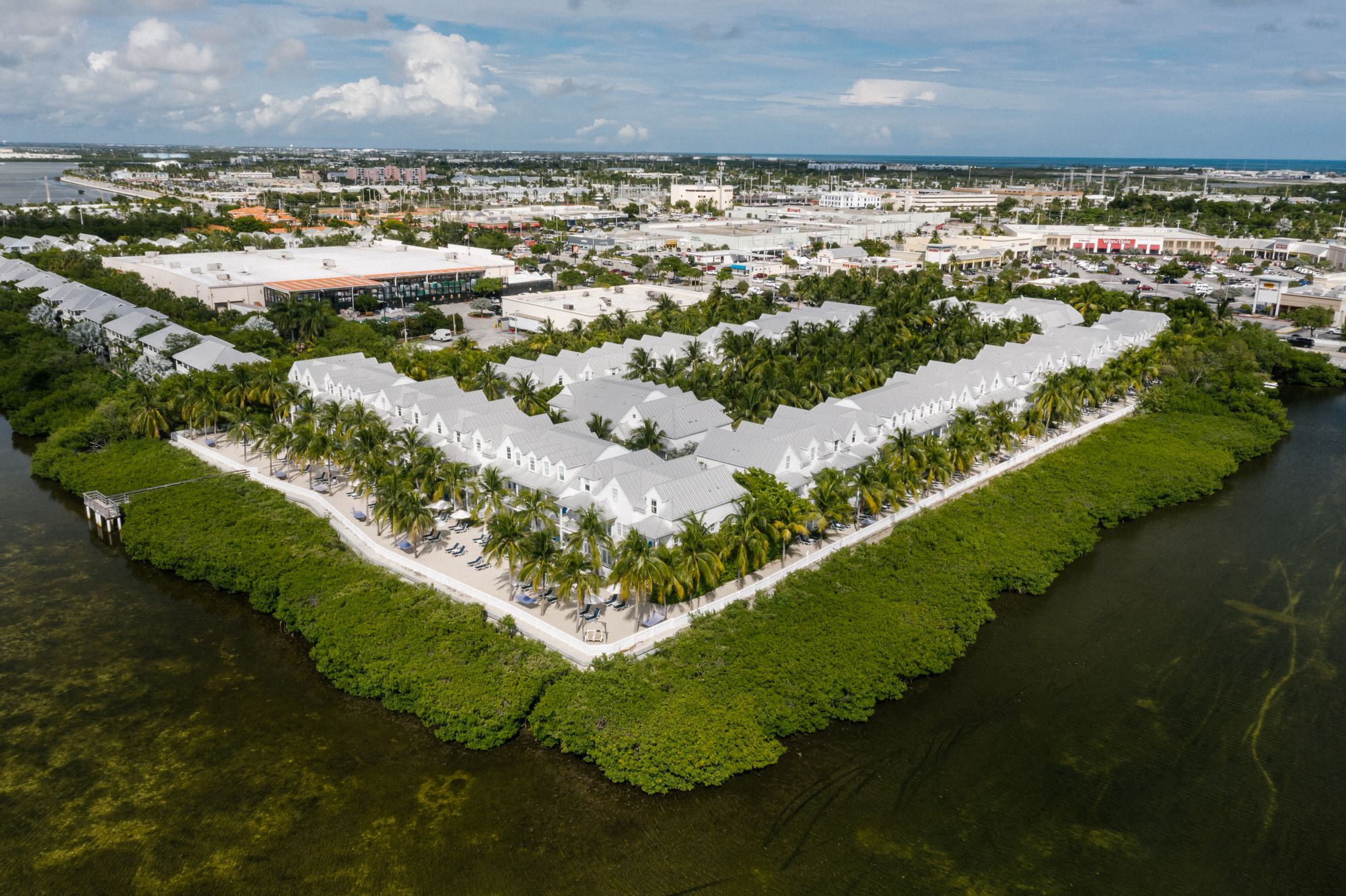 Aerial view of a modern white waterfront estate with private dock on the Intracoastal at sunrise