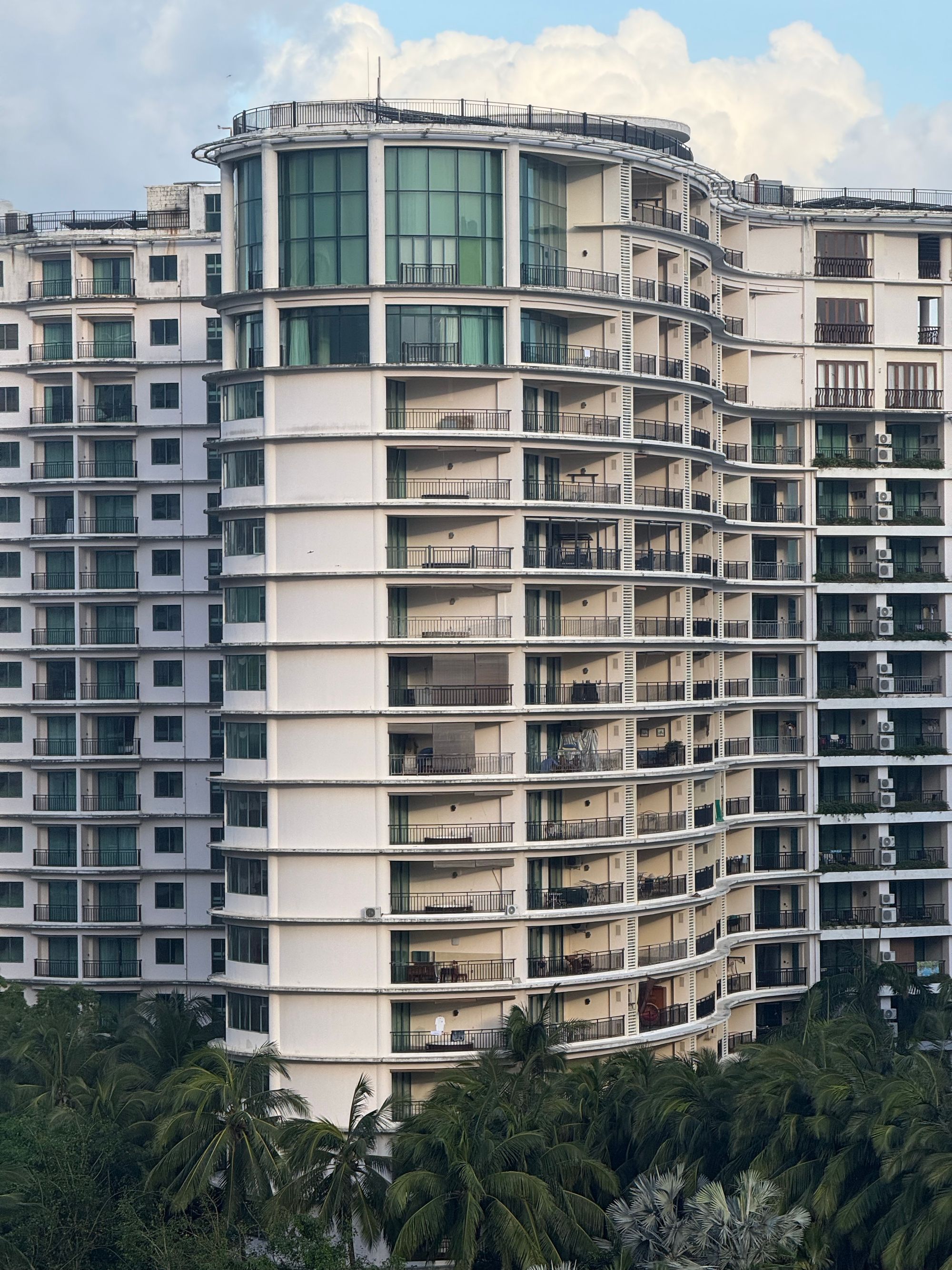 Waterfront luxury condominium buildings lined with palms at sunrise